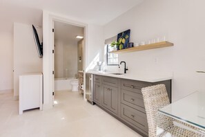 A modern kitchen with a white refrigerator, grey cabinets, and a glass dining table. - Casa Valerio Unit 6D (Santa Barbara)