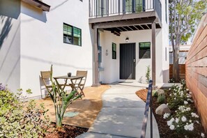 A modern house with a patio, a dining area with chairs, and a pathway leading to the entrance. - Casa Valerio Unit 6D (Santa Barbara)