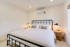 A neatly made bed with a white comforter and patterned pillows, a black metal headboard, and two bedside tables with lamps. - Casa Valerio Unit 6D (Santa Barbara)