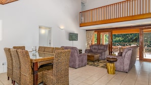 Ein geräumiger Wohnbereich mit Esstisch, Sofas und einem Balkon mit Holzgeländer.