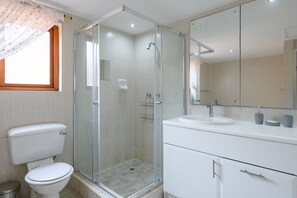 A modern bathroom with a glass-enclosed shower, a white toilet, and a vanity with a mirror. - San Lameer Villa Rentals 10301 (Southbroom)