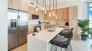 A modern kitchen with a stainless steel refrigerator, a microwave, and a large island with bar stools.