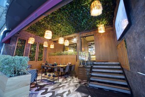 A restaurant with a modern interior, featuring a wooden table and chairs, hanging lights, and a staircase leading to an upper level. - Dosso Dossi Hotels Laleli (Istanbul)