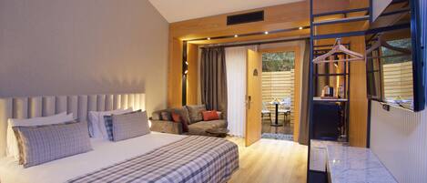 A modern hotel room with a large bed, a desk, and a seating area with a sofa and chairs.