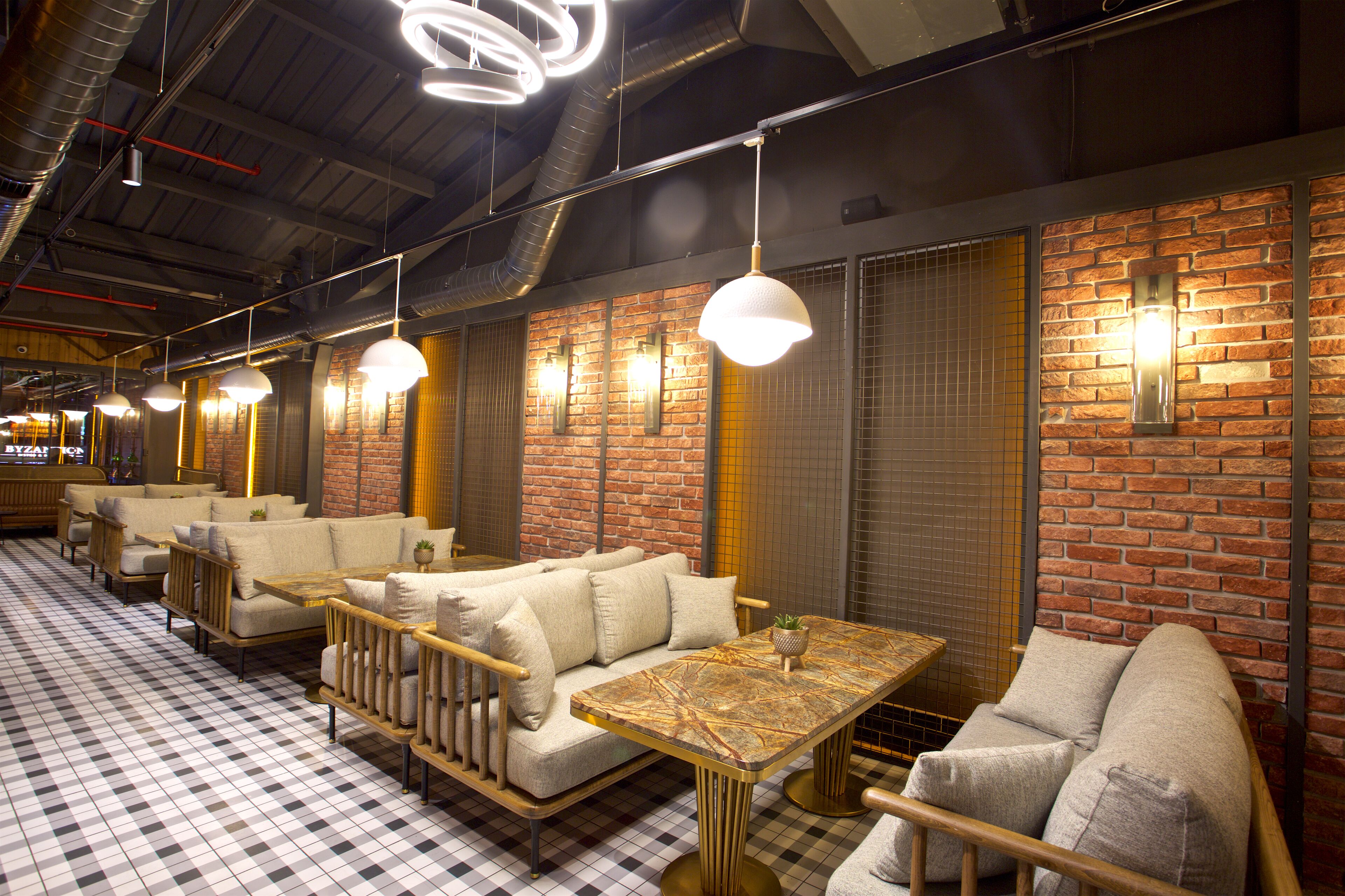 A restaurant with brick walls, checkered flooring, and multiple seating areas including sofas and tables.