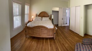A bedroom with a wooden bed, a chair, and a wardrobe. - 1st Class Rentals Munson Manor VIII at 1 Columbia Street a 1 Bedroom Apartment (Oneonta)