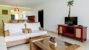 A living room with a sofa, television, and a cabinet. - Private Beach Club & Amazing Golf- Yours to enjoy, with unlimited free golf. (Punta Cana)