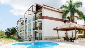 A hotel with a swimming pool, outdoor seating, and a covered area. - Private Beach Club & Amazing Golf- Yours to enjoy, with unlimited free golf. (Punta Cana)