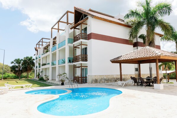 A hotel with a swimming pool, outdoor seating, and a covered area.