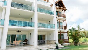 A multi-story hotel with balconies, a covered outdoor seating area, and a lush garden. - Private Beach Club & Amazing Golf- Yours to enjoy, with unlimited free golf. (Punta Cana)