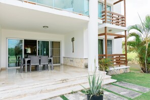 Een modern herenhuis met een overdekt terras, een eethoek met stoelen en een trap naar de bovenverdieping.