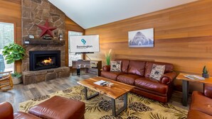 A cozy living room with a stone fireplace, leather furniture, and a sign for Bennington Carpentry. - DESC08 - Lovely Home, Foosball, Hot Tub, Sauna (Sunriver)