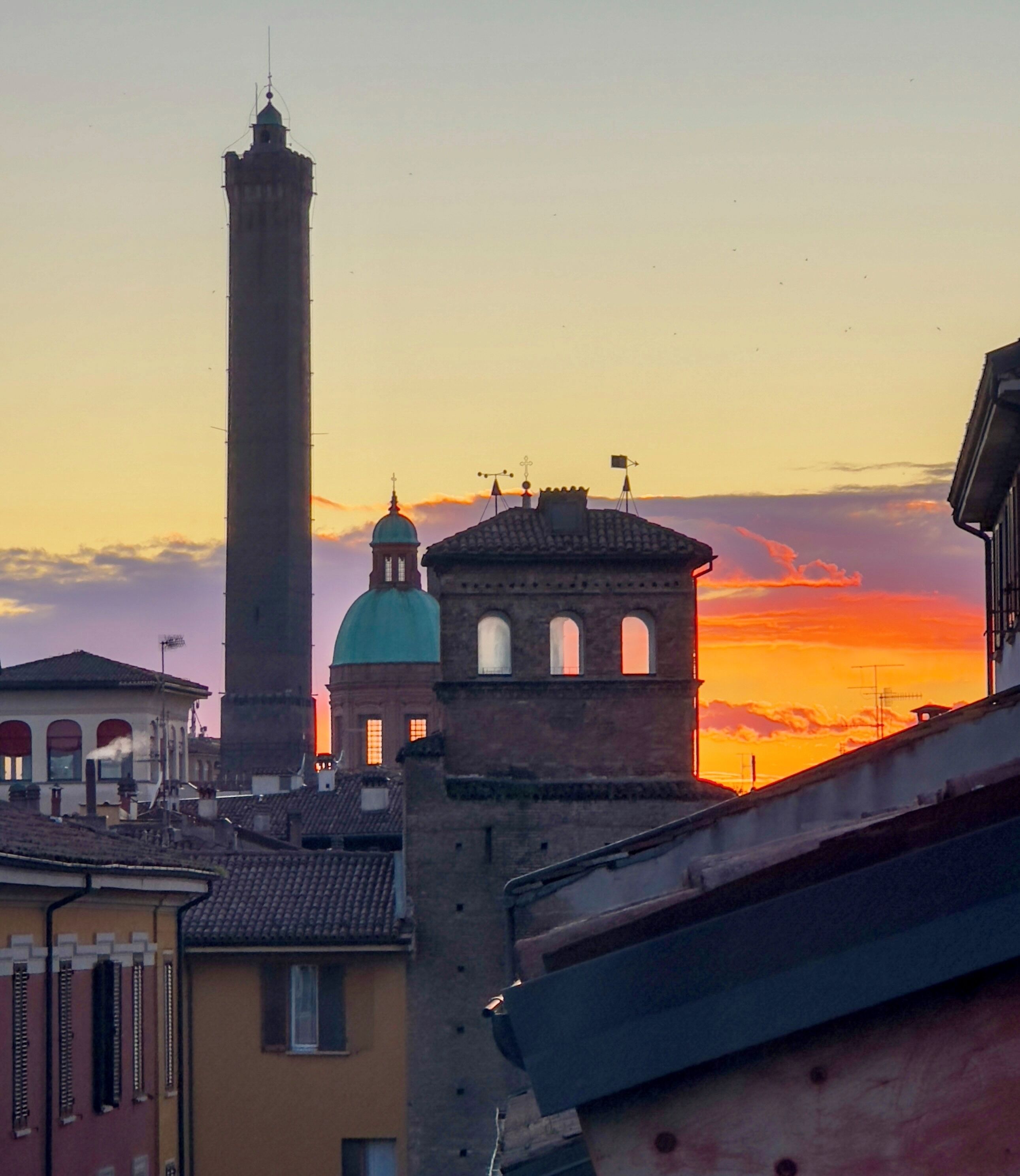 Un edificio histórico con una torre destacada y una cúpula, frente a un cielo al atardecer.