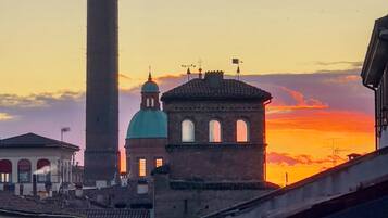 Un edificio histórico con una torre destacada y una cúpula, frente a un cielo al atardecer.