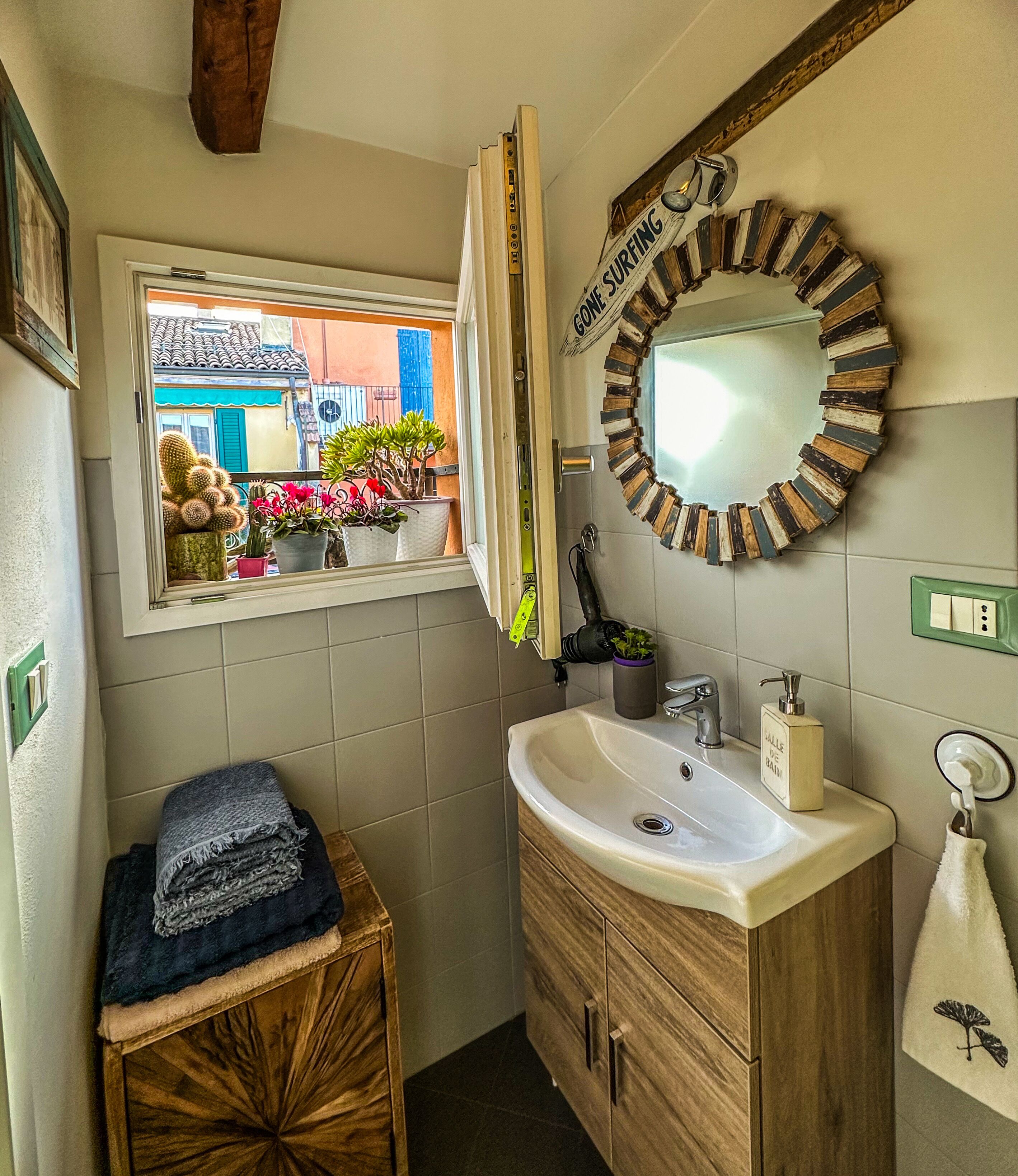 A bathroom with a window, a sink, a mirror, and a towel rack.