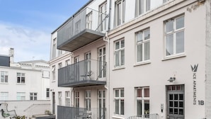 Un edificio residencial de varios pisos con balcones, una escalera y una entrada con reja.