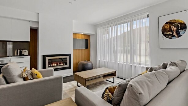 Un salon moderne avec une cheminée, un canapé, une table basse et un téléviseur.