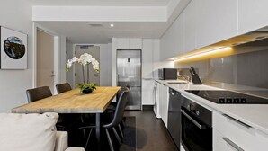 Une cuisine moderne avec une table à manger en bois, des chaises noires et des meubles de rangement blancs.