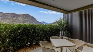 Une terrasse avec une table et des chaises, un palmier et une vue sur les montagnes.