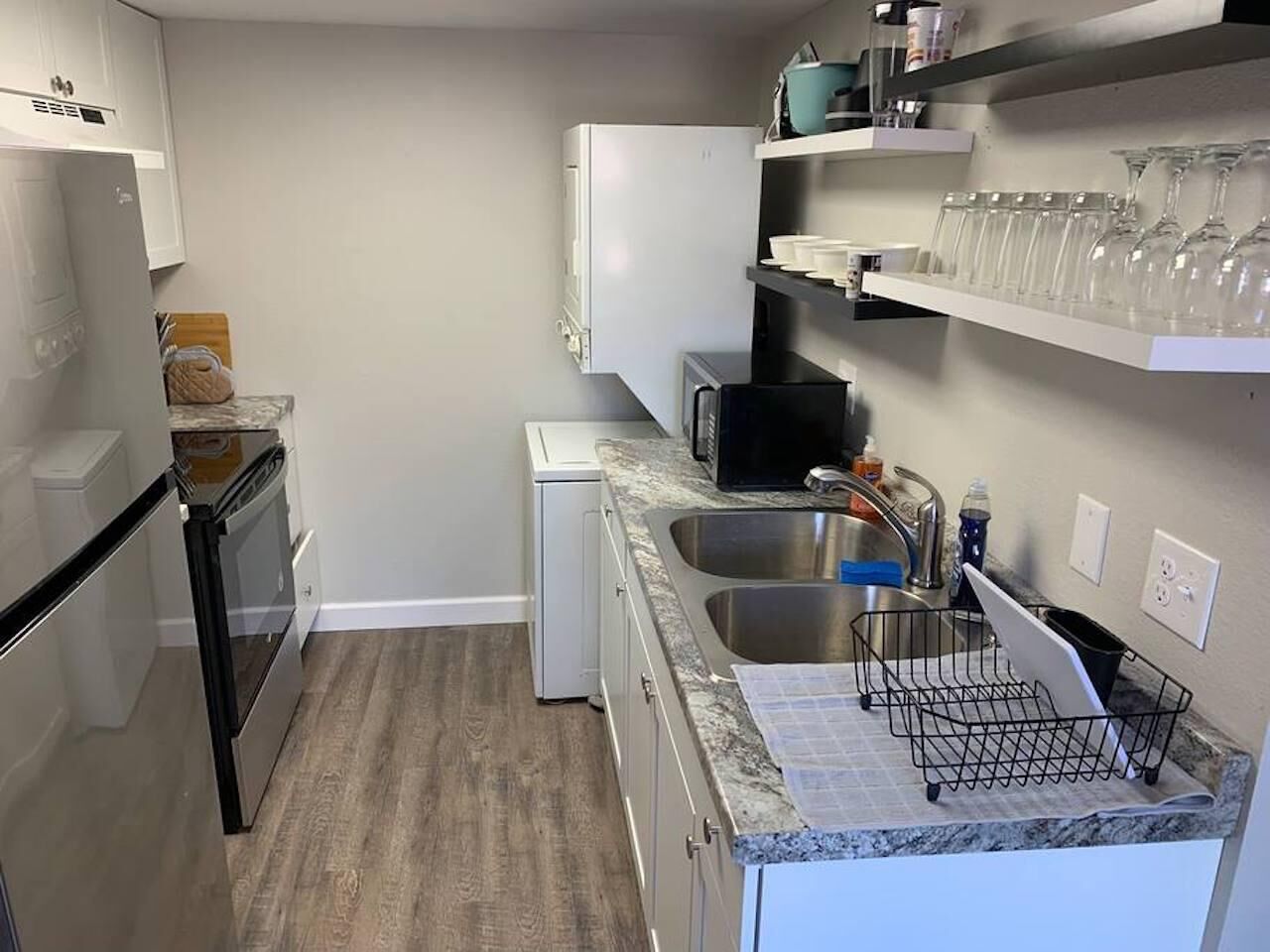 Cocina compacta con refrigerador, microondas, lavaplatos y lavadero pequeño.