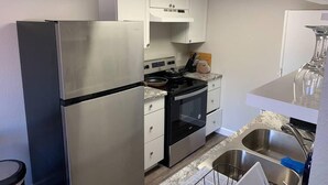 A compact kitchen with a stainless steel refrigerator, a built-in oven, and a sink.