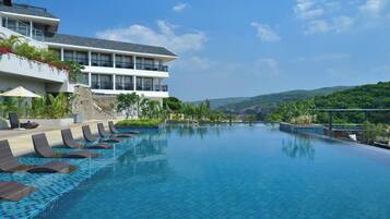 A hotel with a large infinity pool, a multi-story building, and a view of the surrounding hills.