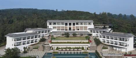 A modern hotel with a central courtyard, multiple balconies, and a swimming pool.