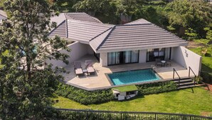 A modern house with a swimming pool, surrounded by lush greenery and other houses. - Courtyard by Marriott Mahabaleshwar (Mahabaleshwar)