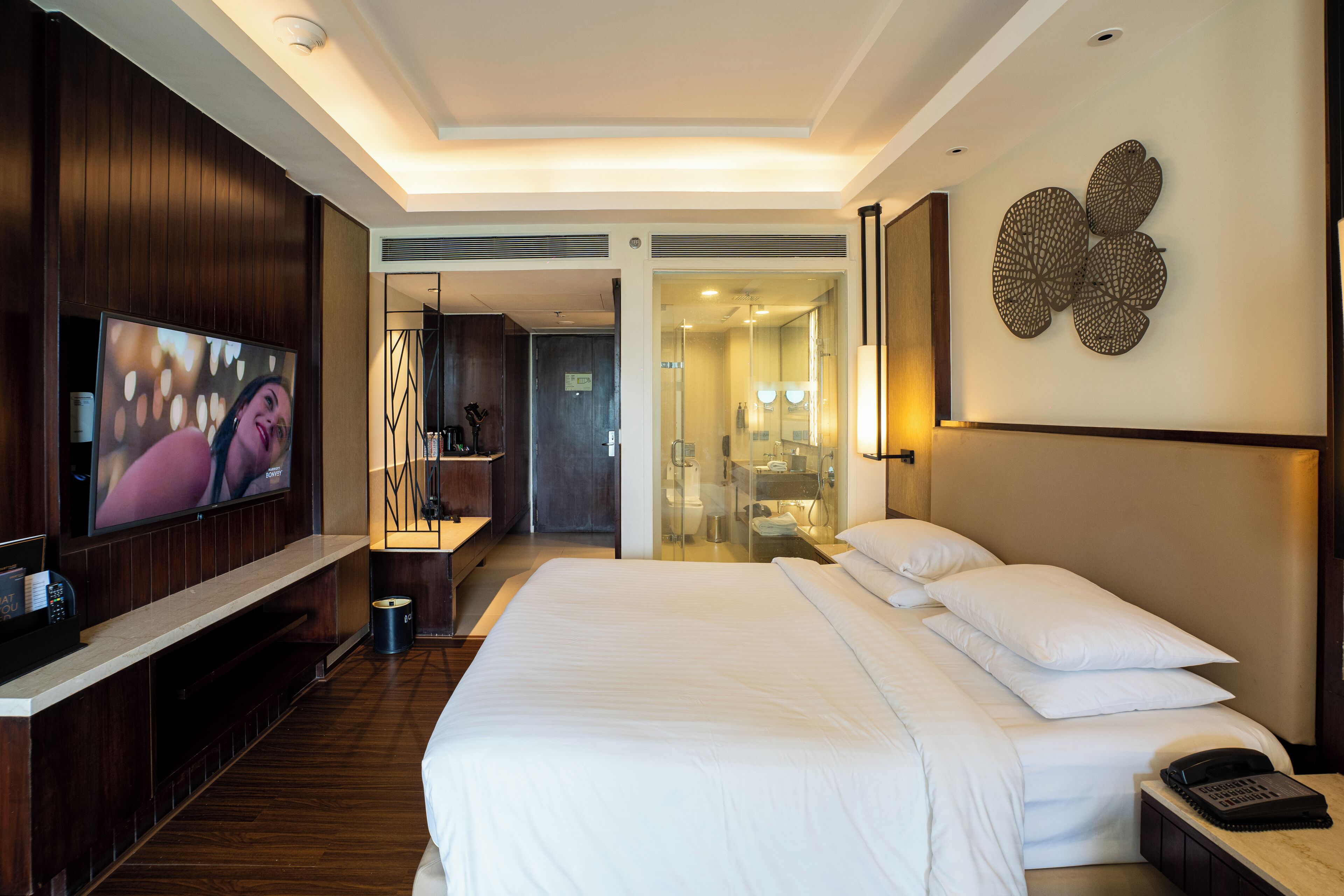 A hotel room with a large bed, a TV, a bedside table, and a wall-mounted artwork.