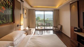 Une chambre d’hôtel avec un grand lit, une petite table, une chaise et un balcon offrant une vue sur les montagnes.