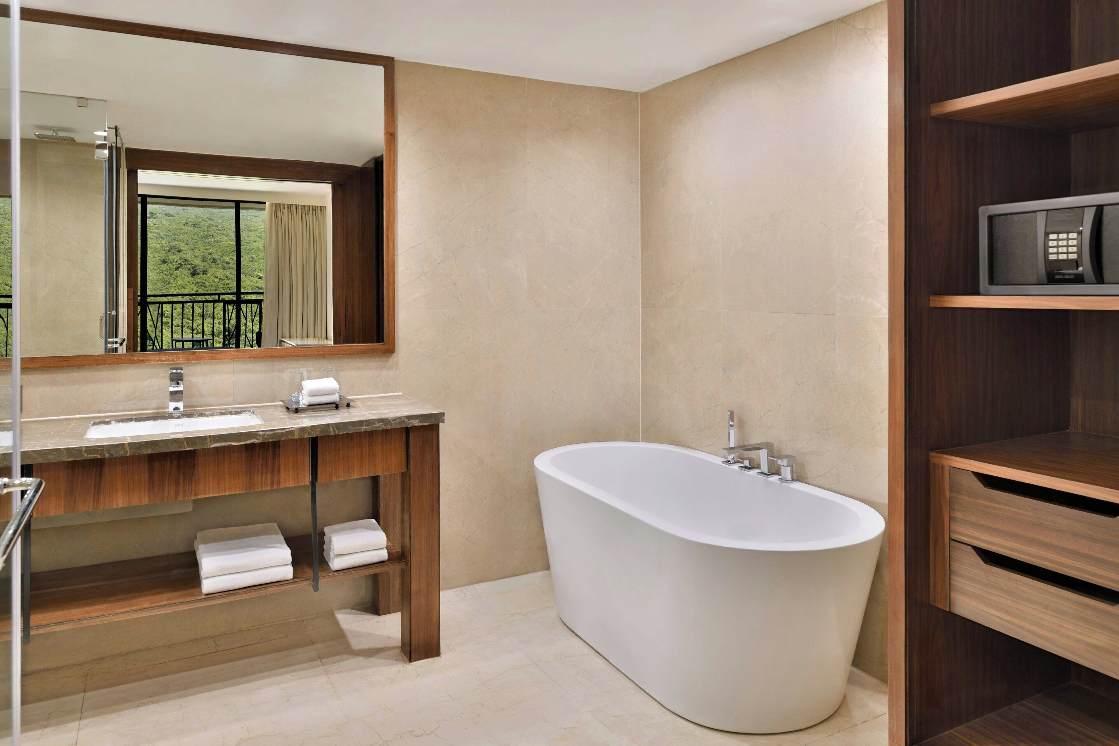 A modern bathroom with a freestanding bathtub, a large mirror, and a wooden vanity.