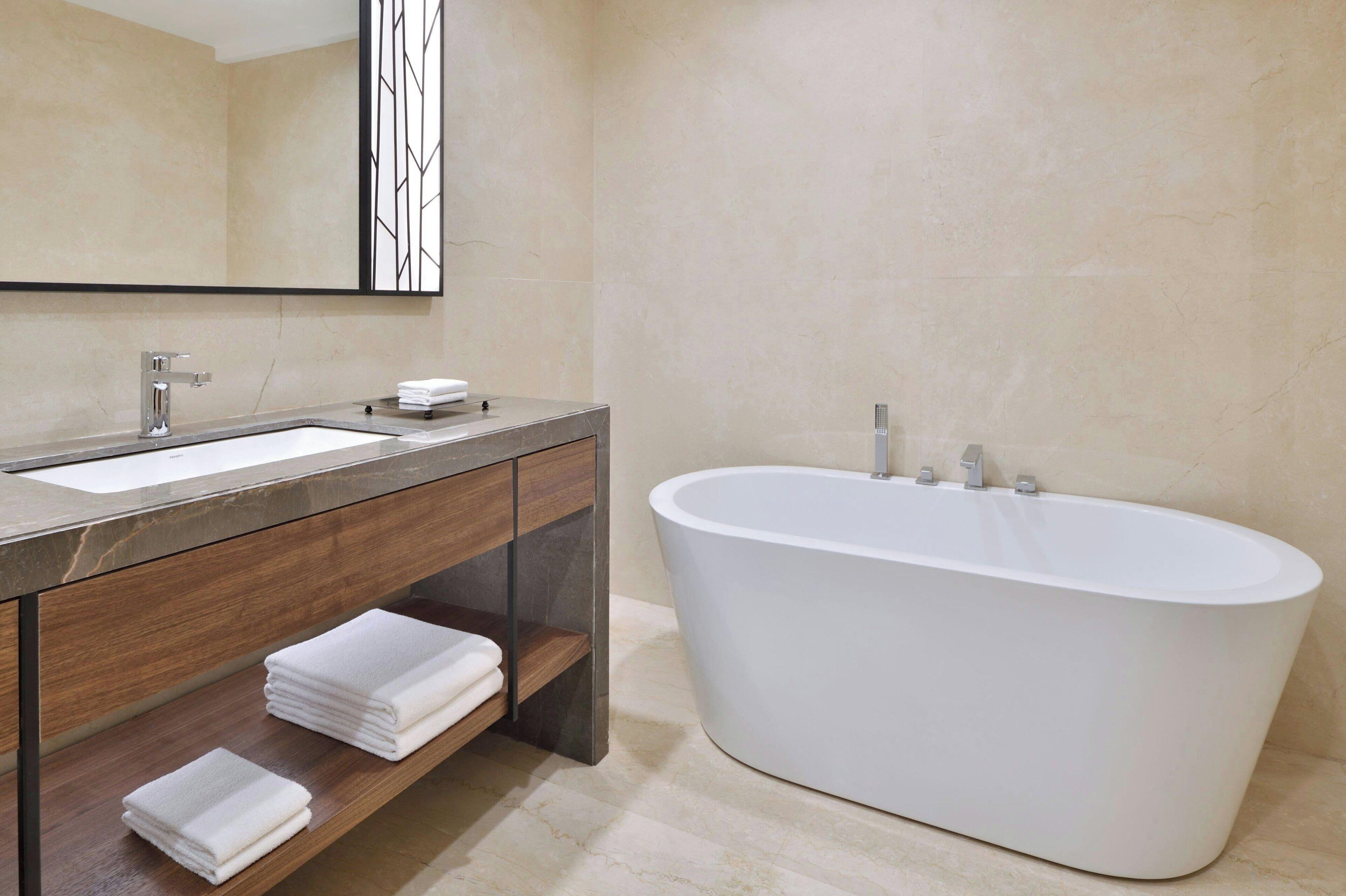 A modern bathroom with a freestanding bathtub, a vanity with a mirror, and two towel racks.