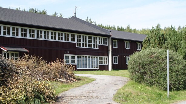 A two-story building with a dark red exterior and white window frames. - Dovreskogen Gjestegård  (Dovre)