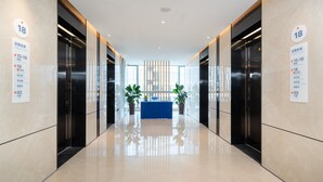 A modern hotel lobby with a blue reception desk, glass walls, and a directory on the walls. - Holiday Inn Express Chengdu High-Tech Zone by IHG (Chengdu)