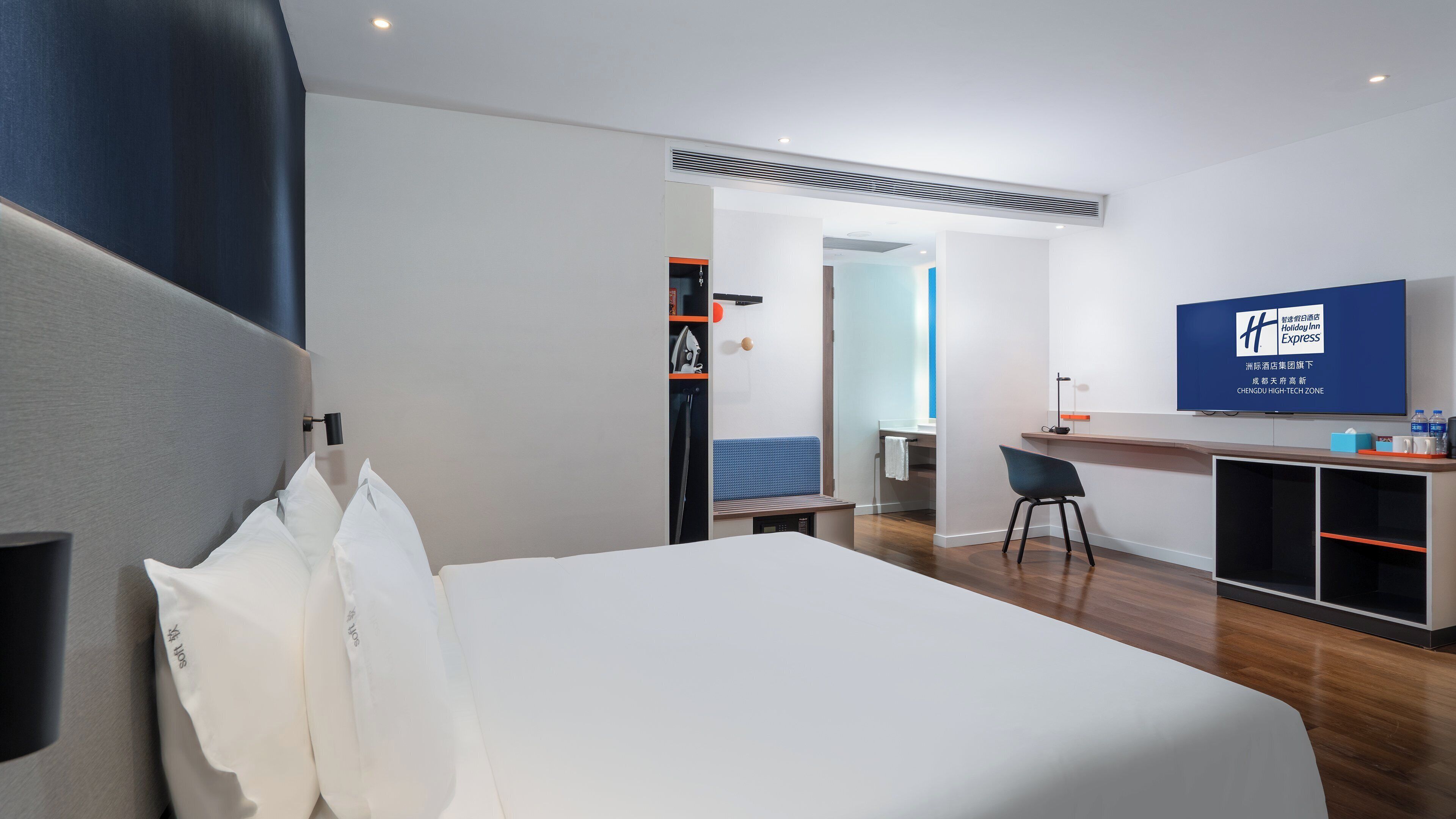 A hotel room with a bed, a desk, a chair, a television, and a wardrobe.