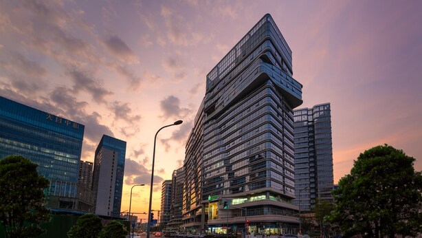 A modern high-rise building with multiple floors, large windows, and a prominent corner design. - Holiday Inn Express Chengdu High-Tech Zone by IHG (Chengdu)