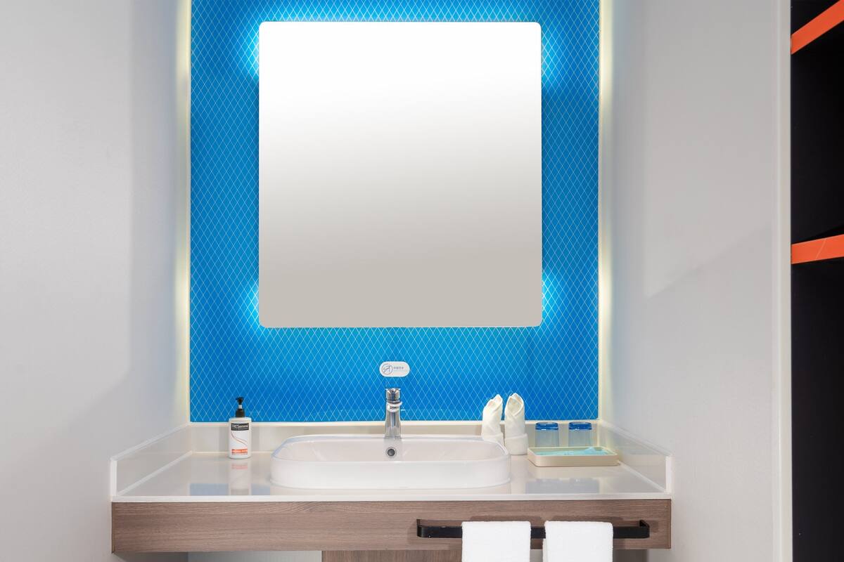 A bathroom with a white sink, a mirror, and a blue tiled wall.