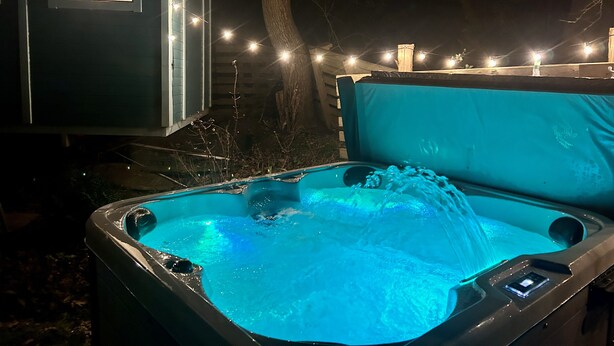 A hot tub with a control panel, surrounded by string lights and a covered area. - Meadowsweet - luxury Shepherd's Hut, amazing views (Herstmonceux)