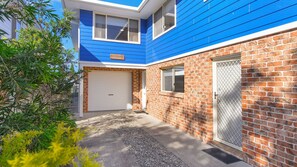 Een woonhuis met een blauwe gevel, een bakstenen gedeelte en een garage.