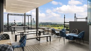 Terraza en la azotea con mobiliario exterior, vistas a la ciudad y equipo de ejercicio.