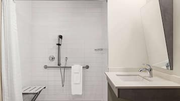 Un baño moderno con ducha, lavamanos y un espejo grande.