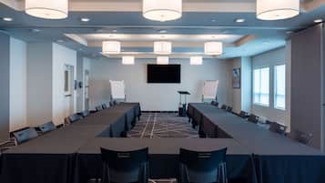 A conference room with long tables, chairs, and a large screen.