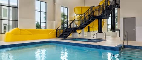 Una piscina interior con un tobogán amarillo y escaleras.