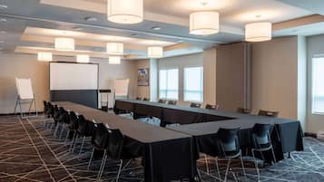 A conference room with a long table, chairs, and a projector screen.