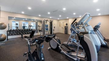 A gym with cardio machines, weightlifting equipment, and a mirror wall.