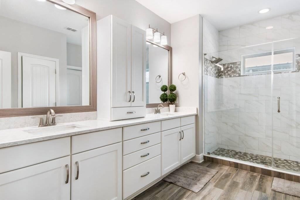 Un bagno moderno con un grande specchio, una doccia e un mobile vanità con cassetti.