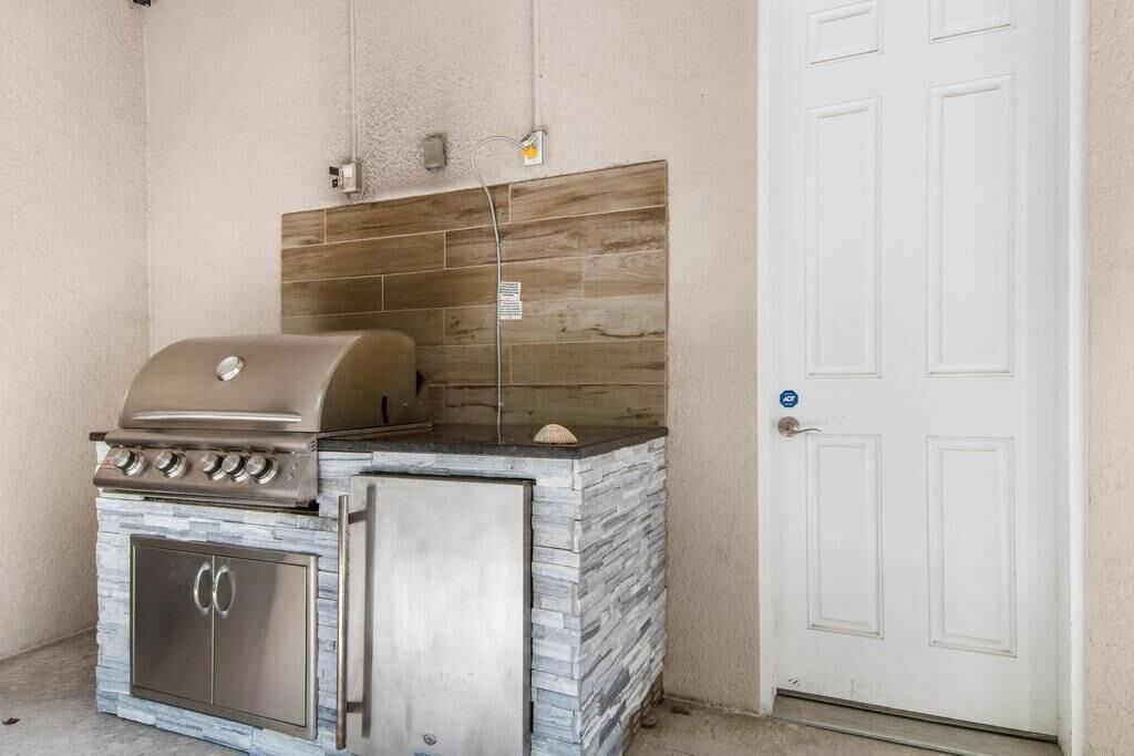 A barbecue grill with a stone facade, a door with a blue lock, and a wall-mounted electrical outlet.