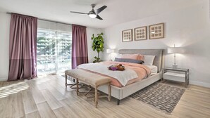 Una camera da letto con un letto, comodini, una ventola a soffitto e vista sull'esterno.