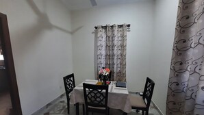 Un pequeño comedor con una mesa, sillas y una cortina decorativa.