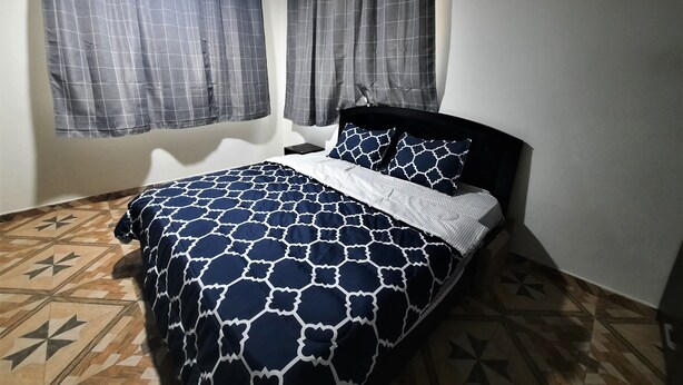 Un dormitorio con cama, cortinas, unidad de aire acondicionado y suelo estampado.
